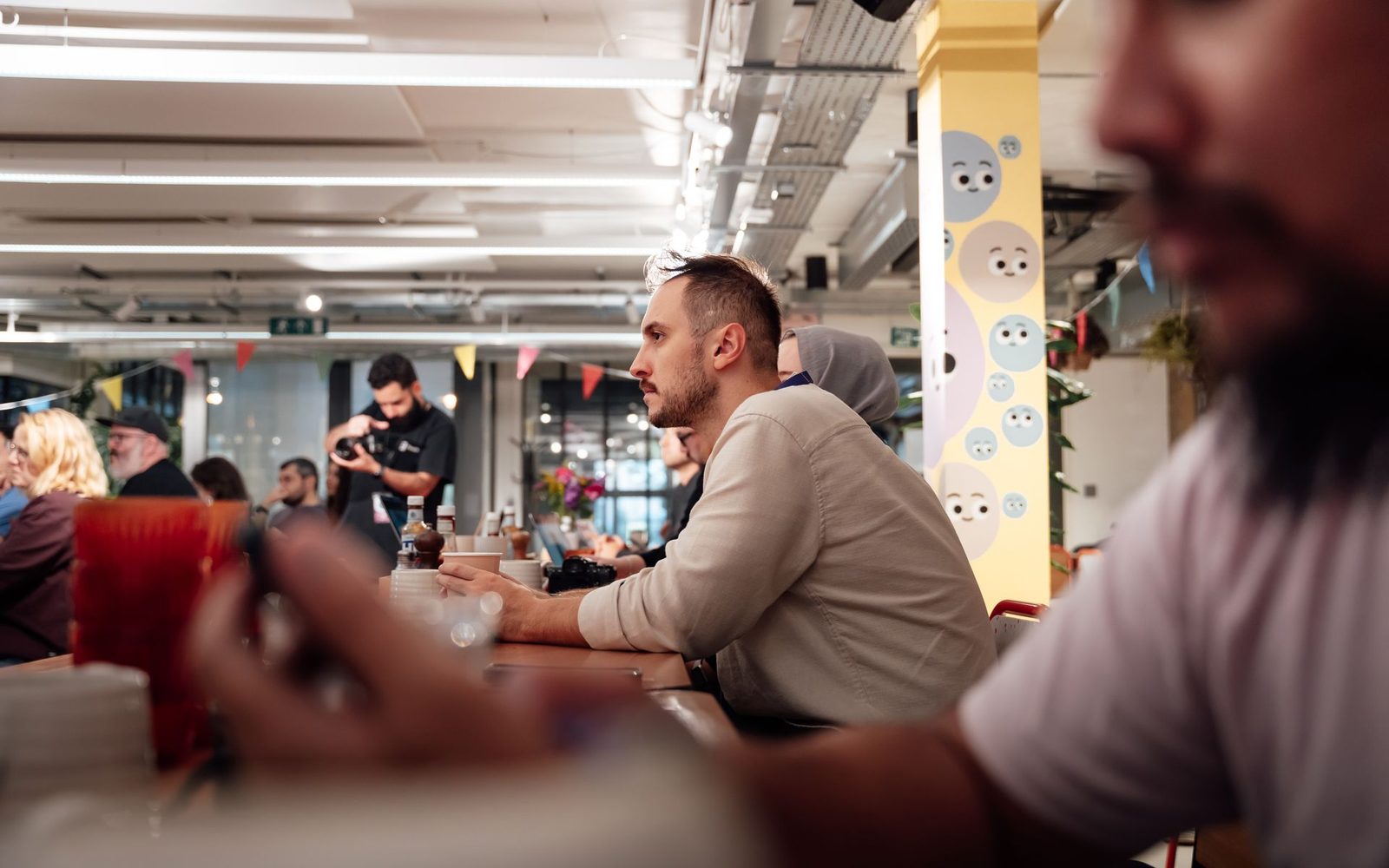 Colleagues working together along a long shared bench in a busy open-plan London office